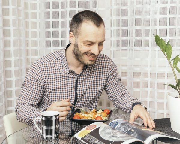 man-reading-magazine-dinner-min